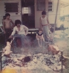 The Leo Johns family roasts a couple of young pigs. Marie Rivera and Johnny Johns turn the spits. Myers Amusements. 1970's.jpg